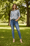 Model wearing the Zola Leopard Shirt with skinny jeans in a lush park setting, showcasing stylish elegance.