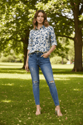 Model wearing the Zola Leopard Shirt with skinny jeans in a lush park setting, showcasing stylish elegance.