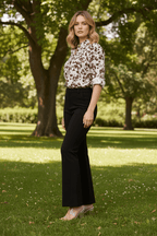 Model wearing the Zola Leopard Shirt with tailored black pants in a sunny outdoor setting.