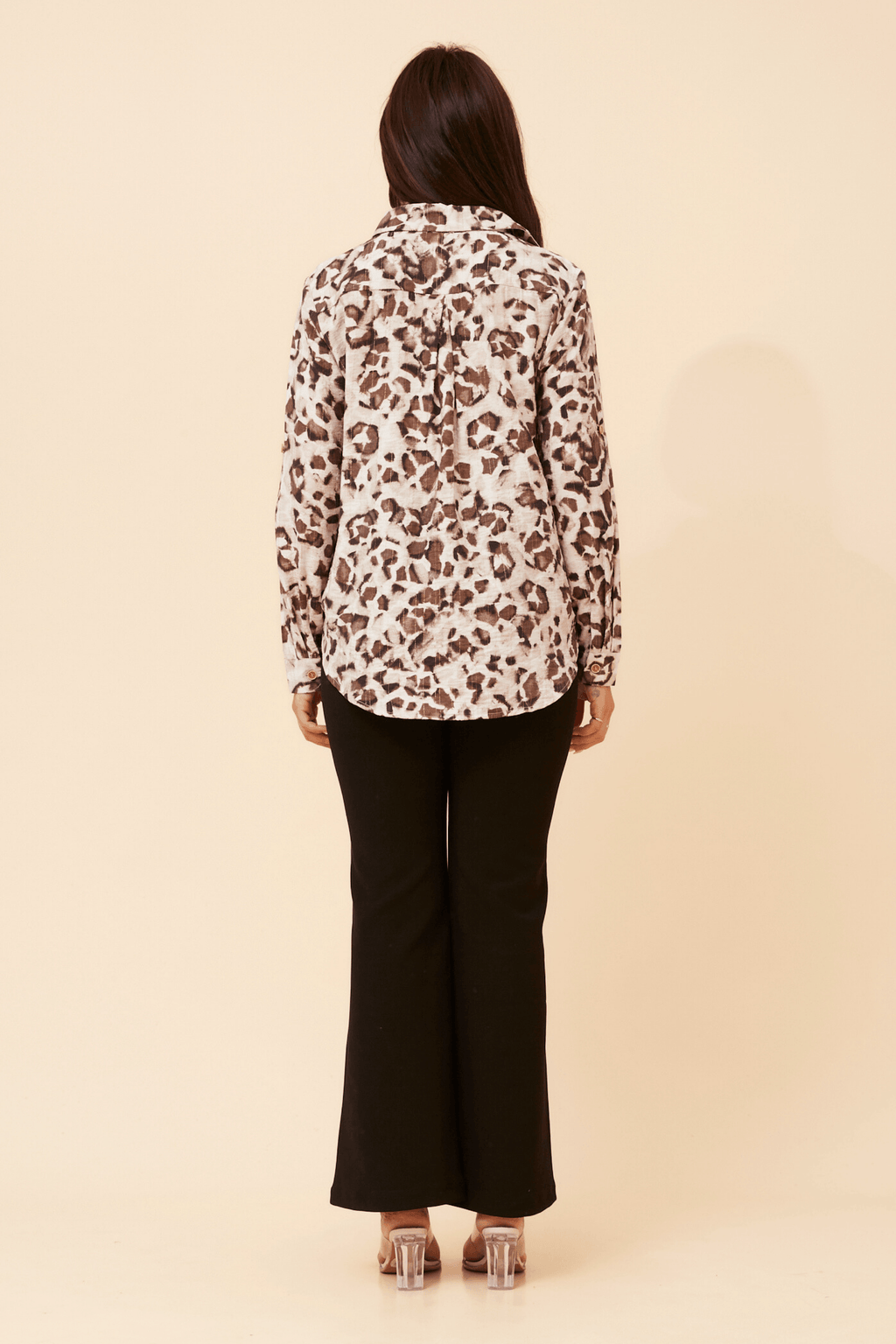Back view of a woman wearing the Zola Leopard Shirt paired with black pants, showcasing the stylish leopard print design.