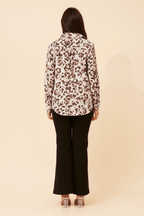 Back view of a woman wearing the Zola Leopard Shirt paired with black pants, showcasing the stylish leopard print design.