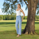 Model wearing Jerry High Waist Jeans standing by a tree in a scenic outdoor setting, showcasing the high-rise fit and wide leg silhouette.