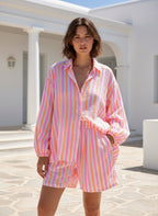 Model wearing Candy striped Shorts and a matching shirt in pink, white, and orange stripes, ideal for sunny days.