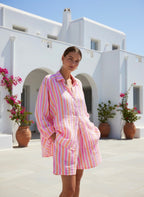 Candy striped Shorts in pink, white, and orange hues worn by a woman in a sunny outdoor setting.