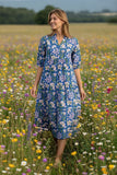 Model wearing Minnesota Midi Dress surrounded by colorful wildflowers in a sunny field.