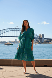 Model wearing the Juni Satin Midi dress by the Sydney Harbour, showcasing its tiered design and floral pattern.