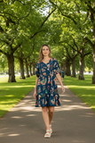 Model wearing Arriba Dress Navy walking in a tree-lined park, showcasing its vintage Mexican western vibes.