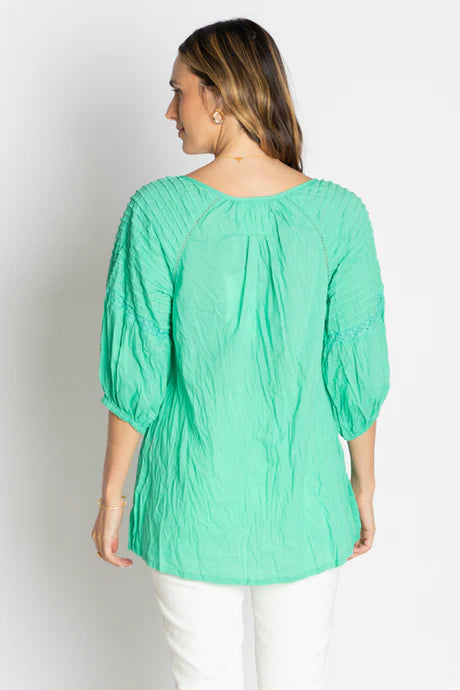 Back view of woman wearing the Celeste Top in vibrant green, showcasing its relaxed fit and unique puff sleeves.