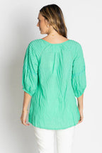 Back view of woman wearing the Celeste Top in vibrant green, showcasing its relaxed fit and unique puff sleeves.