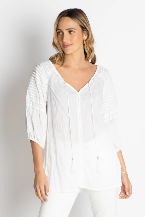 Model wearing the Celeste Top, a white cotton blouse with scooped neckline and delicate ties for a bohemian look.