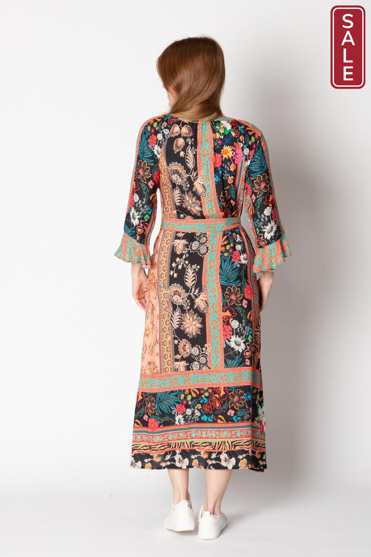 Back view of Gisele Midi dress with flared cuffs, colorful floral patterns, and optional waist tie, displayed on a model.