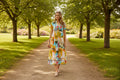 Model walking in sunny park wearing the Rayna Midi with vibrant tropical print and Nauru collar.