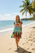 Model wearing the Talullah Dress Multi on a beach, featuring a vibrant multi-colored print and relaxed vibe.