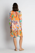 A model showcasing the colorful back view of the Quintana Dress with floral patterns and three-quarter sleeves.