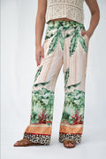 Woman wearing SIS Palm Tree Pant with tropical print and leopard border, showcasing stylish wide-leg design.