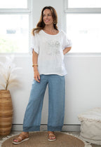 Model showcasing Pari Linen Pants with a stylish white top in a bright room, highlighting comfort and elegance.
