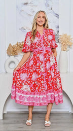 A model showcases the Pineapple Shirt Dress red with a belted waist and floral design, perfect for any occasion.