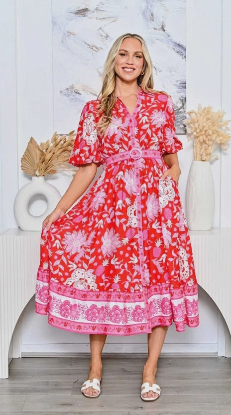 A model showcases the Pineapple Shirt Dress red with a belted waist and floral design, perfect for any occasion.