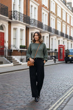 A stylish woman wearing the WL Fiorella Jumper strolling down a charming city street.