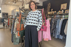 Model showcasing the Freja Love Heart Jumper in a trendy boutique with stylish clothing displays.