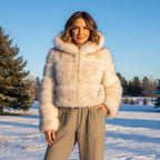 Model wearing Camille Hooded Faux Fur Jacket in snowy landscape with trees.