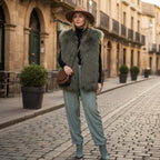 Woman wearing a stylish Mongolian Vest with hat and green pants in a charming street setting.