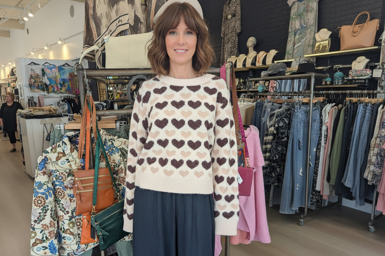 Freja Love Heart Jumper on model surrounded by stylish clothing in a chic boutique.