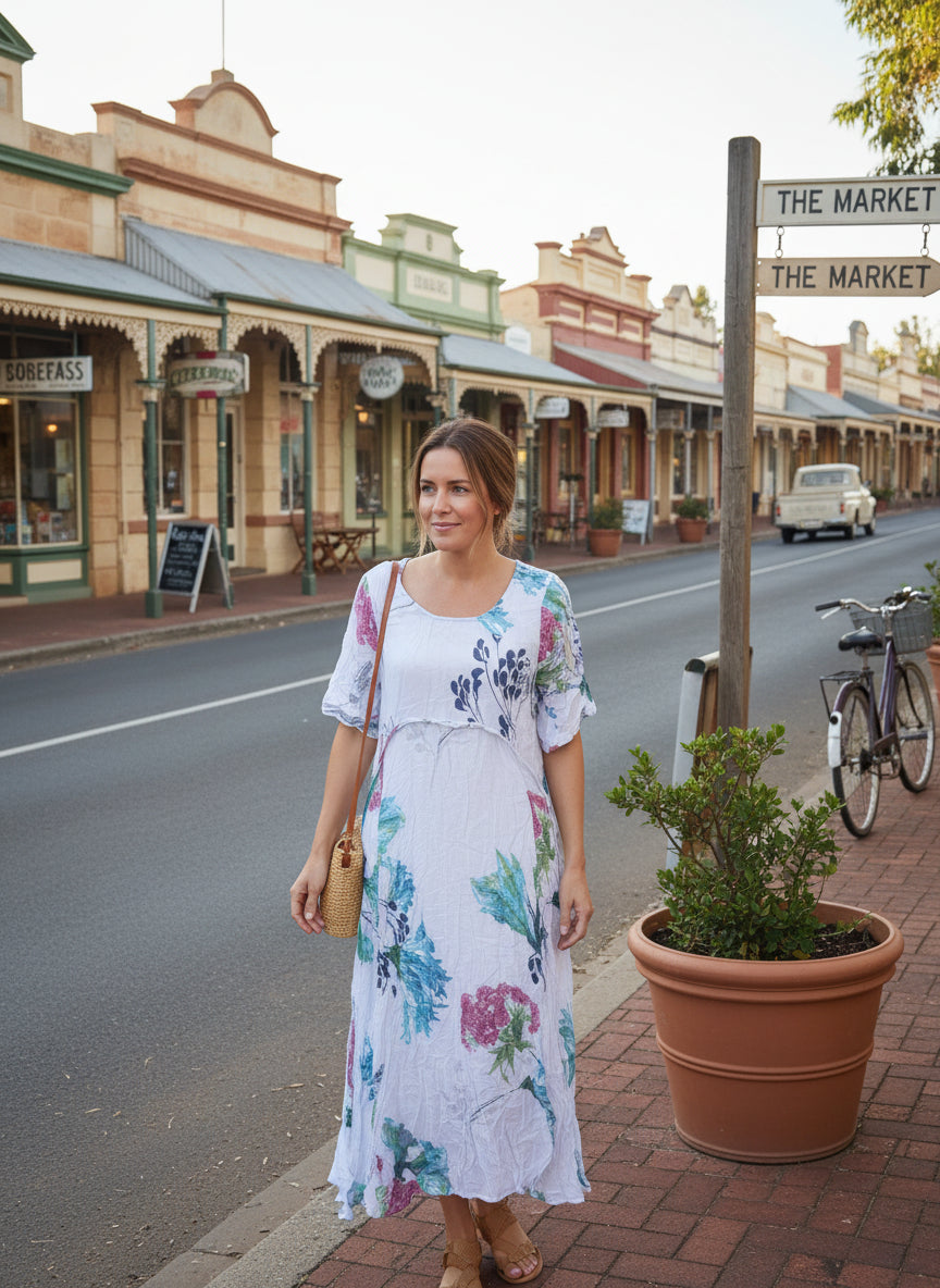 Model wearing the Flora Panel Dress in a charming street setting, showcasing its floral design and short sleeves.