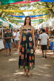 Model wearing Down Under Sundress Black at a vibrant market surrounded by colorful stalls.