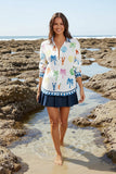 A model wearing the Rubyyaya Rock Lobster Shirt, standing in a rocky beach setting with a cheerful vibe.