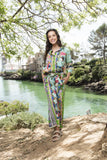 Model wearing Sante Fe Pants by the river, showcasing vibrant colors and a stylish tie waist design.