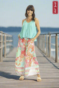 Woman in colorful Orientique Sarah Pant paired with a stylish top, enjoying a sunny day on the pier.