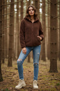 Model wearing a brown Teddy Fur Hood Jacket in a forest setting, showcasing cozy style and practical design.