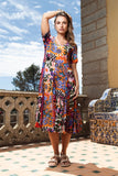 Model wearing a colorful Salvador Godet Dress in a sunny outdoor setting, showcasing vibrant print and flattering v-neckline.